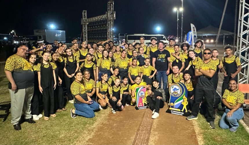 Furiosa Band de Nova Alvorada do Sul celebrando a vitória no Campeonato Sul-Mato-Grossense de Bandas e Fanfarras em Dourados, com troféus e baliza campeã.